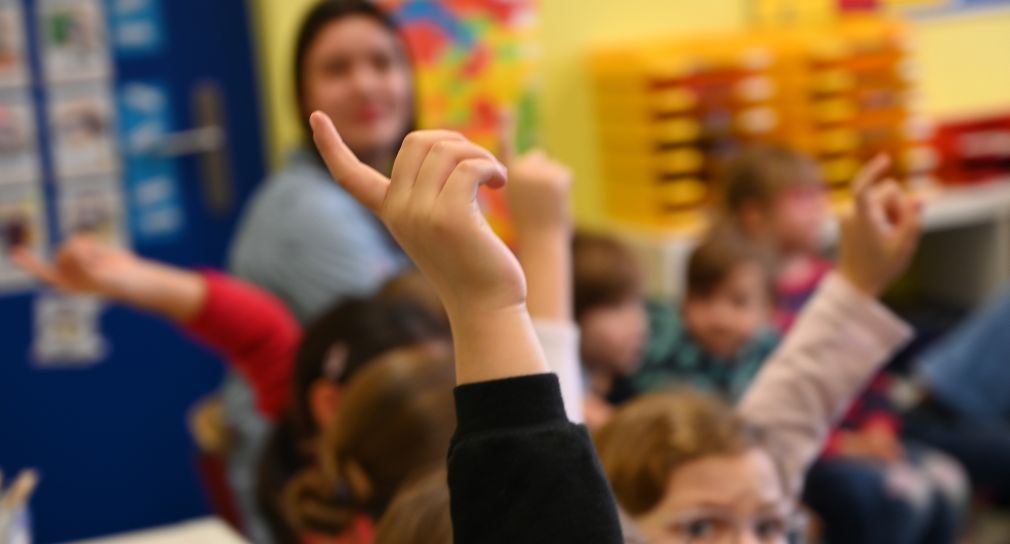 Kinder melden sich mit gestreckten Finger im Unterricht. 